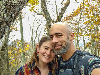 Portrait of young man and woman standing against trees