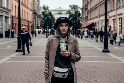 Portrait of young woman standing on street in city