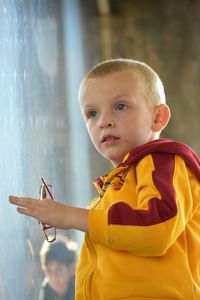 Portrait of cute boy standing against yellow