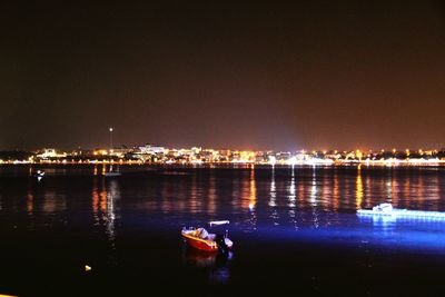 Boats in river with city in background at night