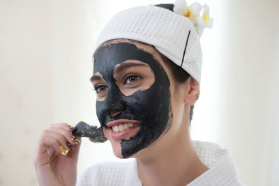 Young woman removing facial mask from face in spa