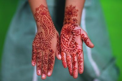 Cropped image of person showing henna tattooed hand