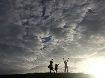 Silhouette people standing against sky during sunset