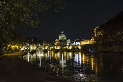 Illuminated bridge over river in city against sky at night