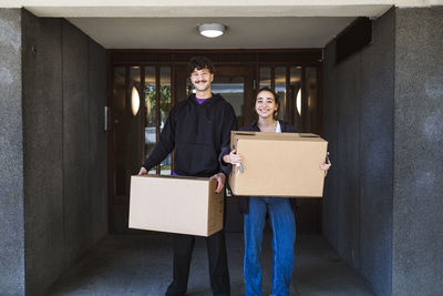 Portrait of smiling couple carrying boxes