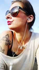 Young woman in sunglasses listening music outdoors