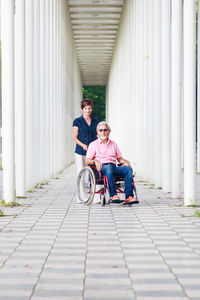 Full length of couple sitting on sidewalk