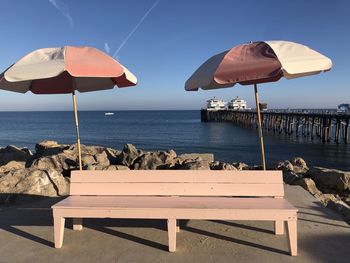 Deck chairs on beach against sky