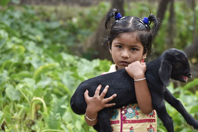 Portrait of girl holding kid goat