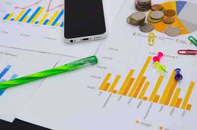 Close-up of bar graphs with mobile phone and office stationery