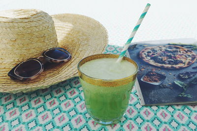 Close-up of drink with hat and sunglasses on table