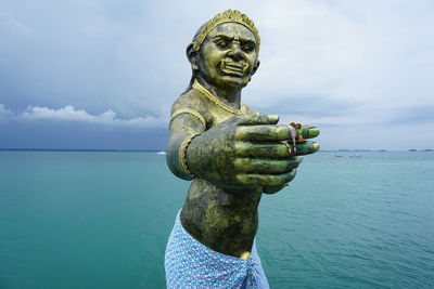 Statue by sea against sky