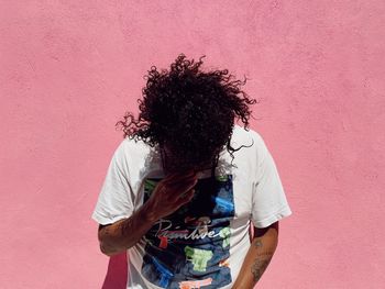 Midsection of woman standing against pink wall