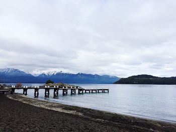 Scenic view of lake by mountains against cloudy sky