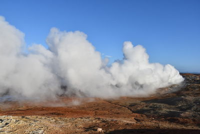 Smoke emitting from volcanic landscape against sky