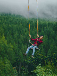 Low angle view of woman swinging on field