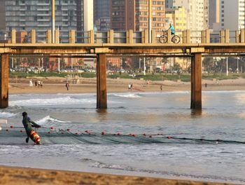 Fisherman pulling fishing net while standing in sea