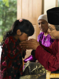 Granddaughter and grandfather holding hands at home