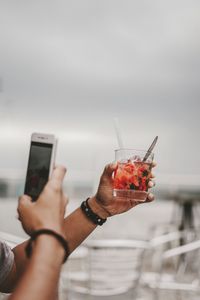 Cropped hands of man photographing drink