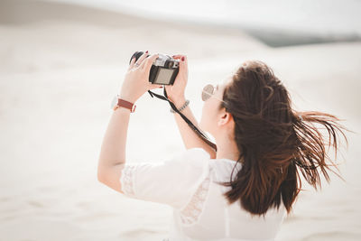 Woman photographing with mobile phone at beach