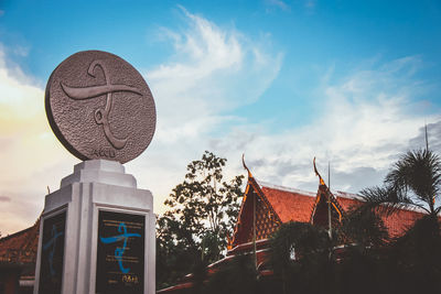Low angle view of sculpture by building against sky