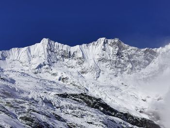 Scenic view of snowcapped mountains against clear blue sky