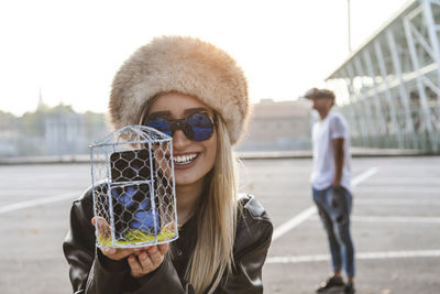 Portrait of woman showing smart phone in container