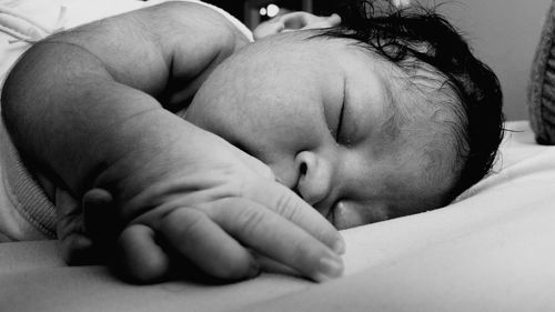Close-up of newborn baby sleeping on bed at home