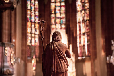 Rear view of man walking in temple against building