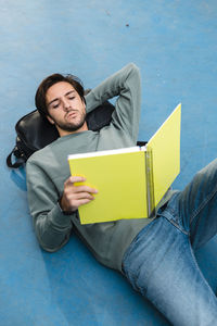 Young man studying while lying on backpack at basketball court