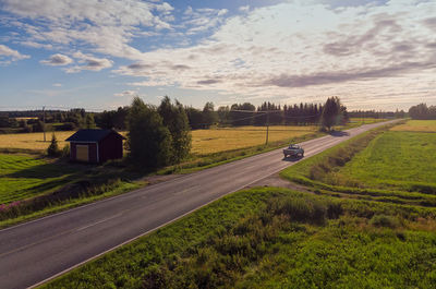 Road amidst field against sky