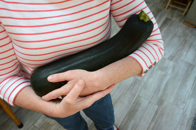 Midsection of woman holding eggplant while standing at home