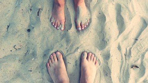 Low section of women standing on sand