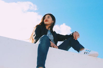 Portrait of woman sitting against blue sky