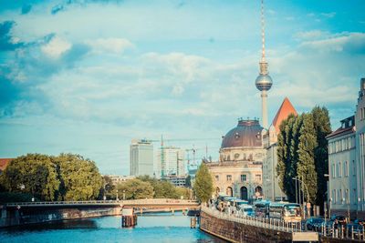 Television tower in city against cloudy sky