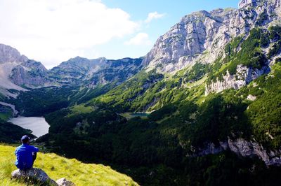 Rear view of woman standing on mountain against sky