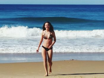 Full length portrait of happy woman standing at beach