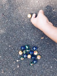 Cropped hand of boy playing marbles on footpath