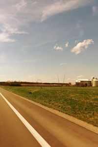 Road amidst field against sky