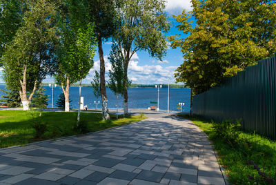 Footpath by lake against sky