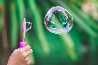 Close-up of hand making bubbles with wand