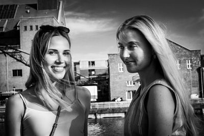 Portrait of beautiful woman in city against sky