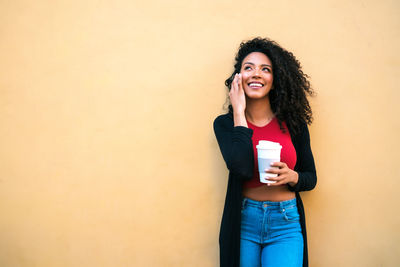 Smiling young woman standing against wall