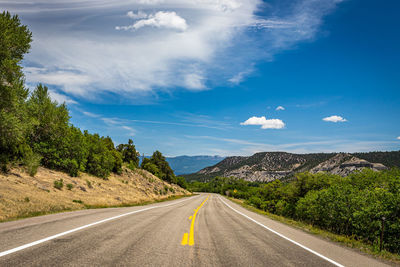 Road leading towards mountains against sky