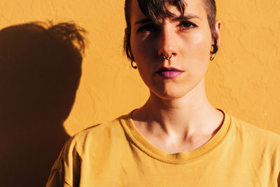 Portrait of woman standing against yellow wall