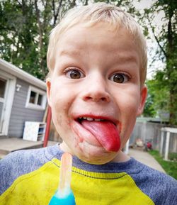 Portrait of boy with sticking tongue out while eating ice cream at yard