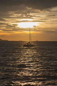 Silhouette of sailboat sailing on sea during sunset