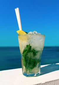 Close-up of beer glass against blue water