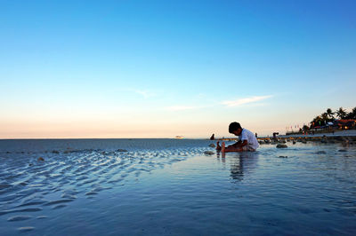 Boy enjoying on shore at beach against sky