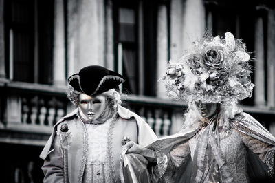 People wearing mask and costume against building during carnival